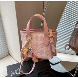 Dettaglio borsa a secchiello a scacchi rosa e bianca con ciondolo a coniglio e finiture d'oro