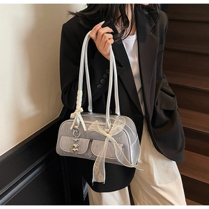 Close-up of silver pleated shoulder bag with white bows and heart charm details