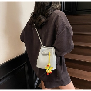 Litchi pattern bucket bag with yellow duck pendant worn over a brown hoodie