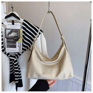 Detail view of cream leather hobo bag with soft pleated texture and adjustable strap