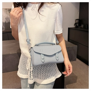 Light blue crossbody bag with double buckle flap shown on model in a modern room
