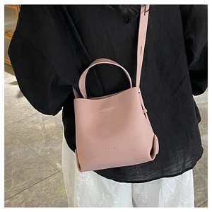Close-up of pink lychee grain leather bucket bag with top handle and adjustable strap