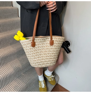 Dettaglio della borsa tote in paglia intrecciata con spalline in pelle marrone
