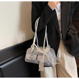 Detail of silver patent leather saddle bag with lace bows and heart charm on a model