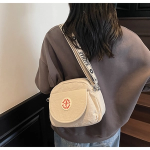 Beige nylon crossbody bag with black printed wide strap and red round logo on side