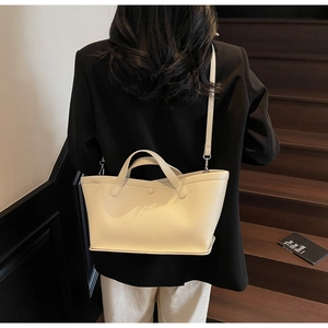 Close-up of cream-colored lychee textured bucket bag worn by model on dark stairs