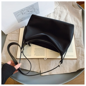 Detail of black moon-shaped tote bag with silver zipper and leather shoulder strap