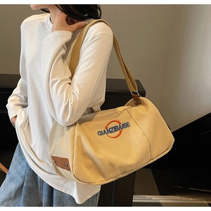 Détail du sac cabas en toile beige avec broderie orange et garniture en cuir marron