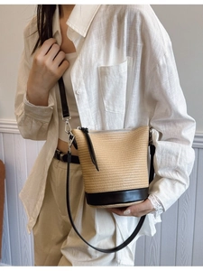 Hollow straw woven bucket bag with black leather bottom and adjustable shoulder strap