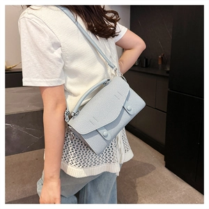 Detail view of light blue denim texture shoulder bag with button flap on female model