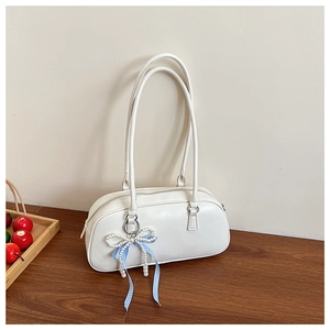 Dettaglio della borsa in ecopelle color crema con ciondolo a fiocco di perle e nastro