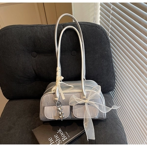 Detail view of silver pleated saddle bag with organza bow and heart pendant on a chair