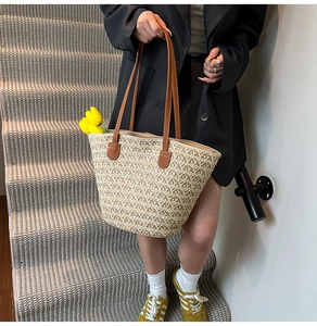 Dettaglio della trama della borsa tote in paglia con manici in pelle marrone e tulipani