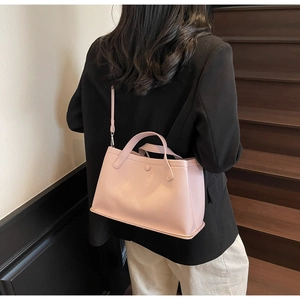 Close-up of pink litchi grain leather bucket bag with top handles and shoulder strap