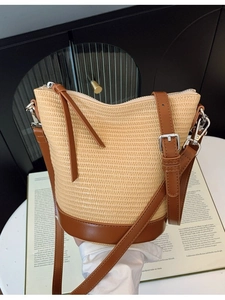Hollow straw bucket bag with brown leather base and adjustable shoulder strap for women