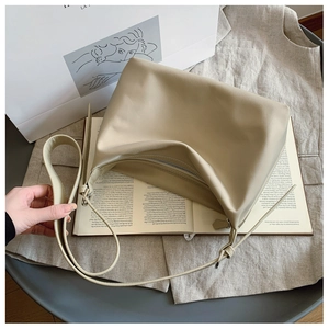 Detail of beige tote bag with silver zipper and wide strap on casual office setting