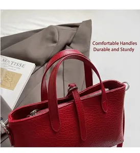 Detail of red crocodile embossed leather handbag with metal zippers and sturdy handles