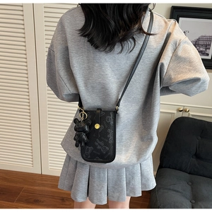 Adjustable crossbody phone bag in black leather featuring a teddy bear embossed pattern