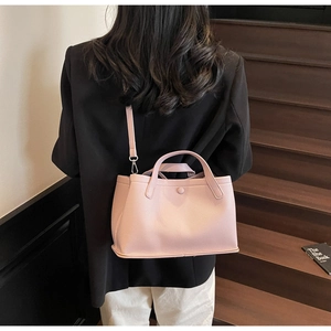 Rear view of a light pink pebbled leather bucket bag styled on a female model