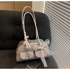 Detail of silver saddle bag with wood grain texture, ribbon bows, and heart pendants