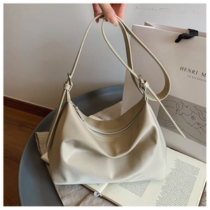 Detail of cream soft leather tote bag featuring adjustable silver buckle and top zipper closure