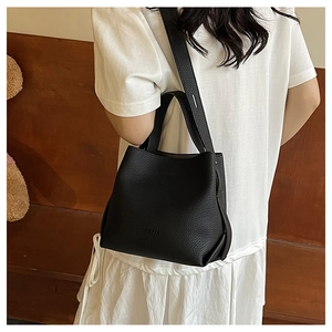 Detailed shot of black lychee grain leather bucket bag with MATCHES logo on wooden bench