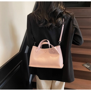 Close-up of pink lychee grain leather bucket bag styled with a black suit on steps