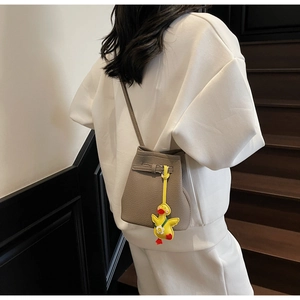 Mini bucket crossbody bag in lychee texture with yellow duck pendant and thin strap