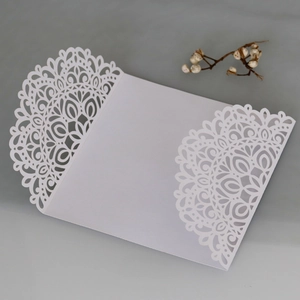 Detail of laser-cut white lace invitation cover with elegant floral patterns on cardstock
