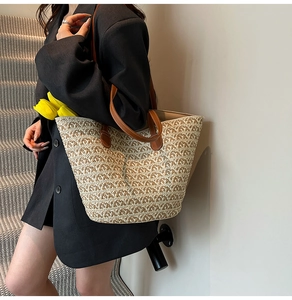 Dettaglio della trama in paglia e dei manici in pelle marrone di una borsa tote