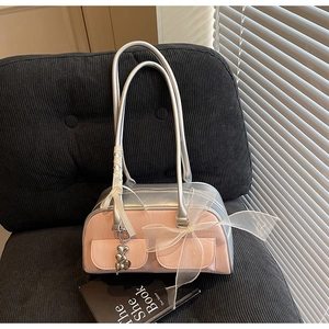 Detail of a pink saddle bag featuring a white mesh bow and a silver heart pendant