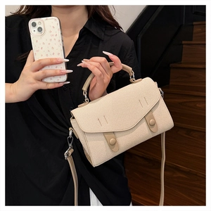 Detail of beige twill fabric handbag with light brown leather handles and classic buckles