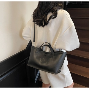 Litchi texture black tote bag shown on a model in a stylish minimalist setting