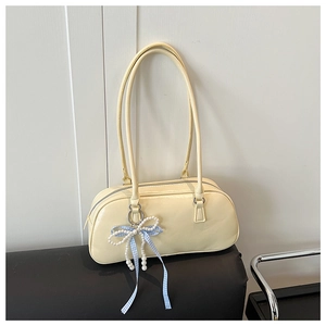 Dettaglio della borsa a spalla color crema con fiocco di perle e nastro a quadri blu
