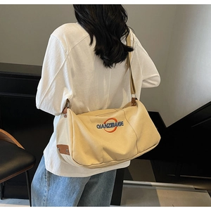 Détail du sac en toile avec broderie logo orange et bandoulière en tissu réglable