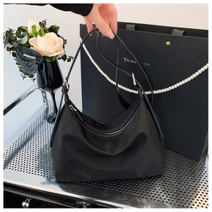 Detail of minimalist black nylon hobo bag with smooth texture and sleek zipper closure