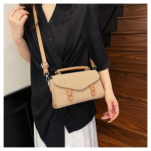 Detail of woven straw crossbody bag with brown leather straps worn by model