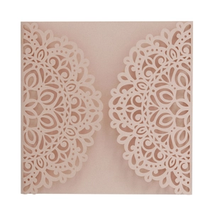 Macro detail of laser-cut mandala pattern on blush pink pearlescent paper invitation