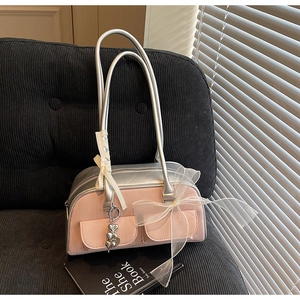 Detail view of pink saddle bag with lace ribbons and large tulle bow on a gray sofa