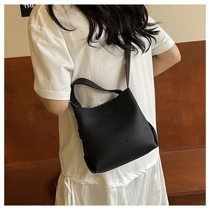 Back view of model wearing a black pebbled leather bucket bag with a thin shoulder strap