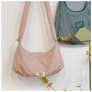 Detailansicht der rosa gefalteten Halbmond-Tasche mit gewebtem Etikett und breitem Gurt