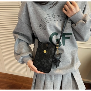 Detail of black crossbody phone bag with grey bear pattern and cute charm