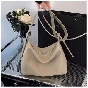 Detailed view of a beige hobo tote bag with adjustable strap in a lifestyle setting