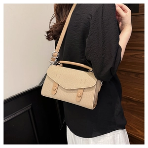 Detail of beige straw texture crossbody bag with envelope flap and decorative buttons