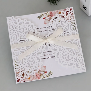 Détail d'invitation de mariage découpée au laser avec insert floral et ruban en satin