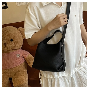 Detail view of black lychee grain leather bucket bag with embossed logo and shoulder strap