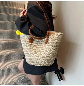 Dettaglio della borsa tote in paglia intrecciata con spalline in pelle marrone e nappa