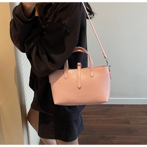 Detail view of pink textured faux leather handbag with adjustable crossbody strap