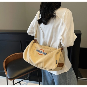 Détail du sac bandoulière en toile kaki avec broderie bleue et sangle réglable