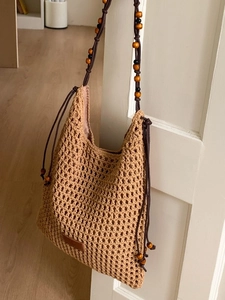 Handmade hollow woven beach tote bag with beaded straps and bohemian style aesthetic